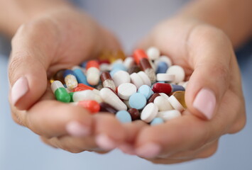 Multi-colored medical pills in female hands. Side effects of drugs concept