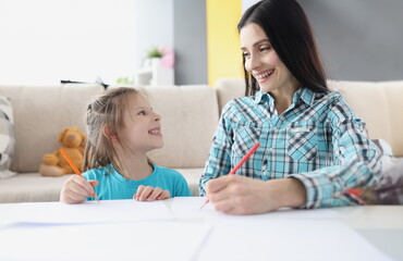 Happy mom and daughter draw with pencils on paper. Development of creative abilities of children concept