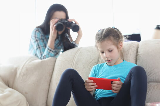 Mom controls her daughter with phone through binoculars. Best parental controls and smartphone apps concept