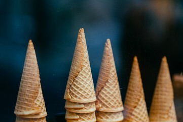 Close up shot of some towers made from crispy ice cream waffle cornets over dark background.