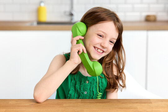 Happy redhead little girl talking on green retro corded phone