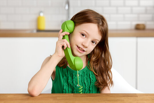 Young girl talking on green retro corded phone