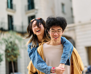 Fototapeta premium woman couple man happy hugging love young together piggyback travel tourist romantic hugging outside city vacation student smile fun relationship joy bonding