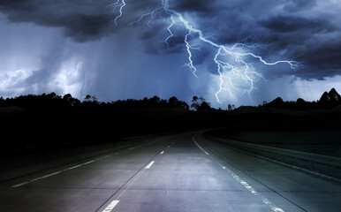 dark night road through forest and mountains, rain and storm with lightning - 648453852