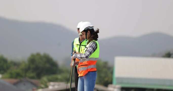 Electrician pulling wire into PVC  pipe electrical engineering female Installing Solar Cell panels on Roof. Solar energy clean and green alternative energy concept.