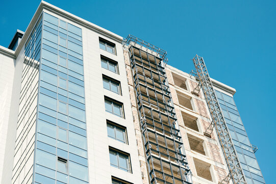 Low angle shot of a modern building in construction with blue sky as background.