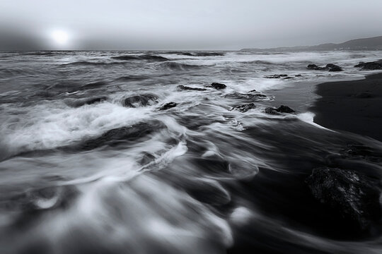 A seascape photographed with a long exposure technique at sunset. Black and white nature landscape.