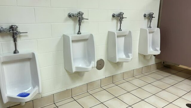 Men's public restroom white porcelain urinals in line. 