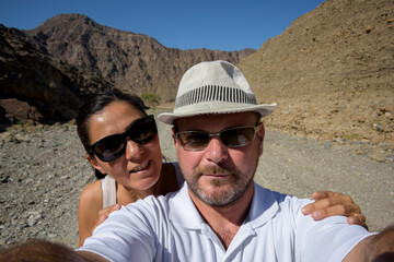 Middle-aged couple captures a Wadi moment in the Middle East with a selfie. People in vacation and traveling 