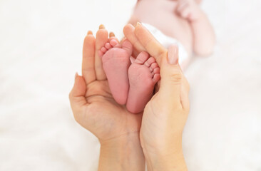 A parent holds the feet of a newborn baby in his hands.