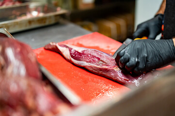 Chef Butcher cutting beef meat with knife on kitchen