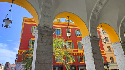 Architectural elements, red buildings, curves and arches of the city. Place Massena, during the day. Nice city, France
