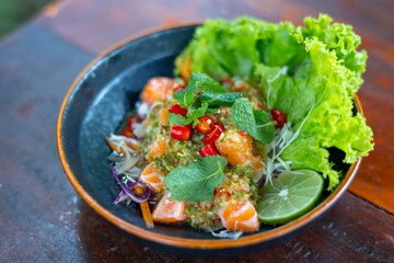 Salmon salad on a plate with vegetables on wooden table. Flavorful salmon salad Spicy It is a popular food of Thai people..