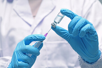 Nurse hand in medical glove holding syringe covid-19 coronavirus vaccine liquid from bottle...
