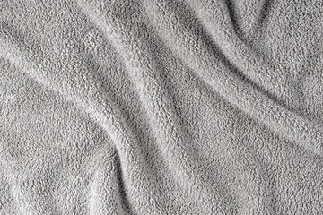 Terry cloth, gray towel texture background. Wrinkled and crumped soft fluffy textile bath or beach towel material. Top view, close up.