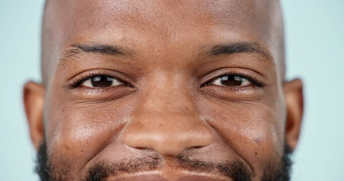 Eyes, closeup and black man with s smile on face for contact lenses, vision or health care on blue background in studio. Happy, portrait and person with healthy skincare, dermatology or wellness