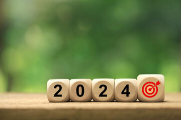 2024 New Year goal plan action. Wooden cubes with 2024 and target icon on a green background. Business plan and development for achieving goals. Goal achievement and success in 2024.copy space