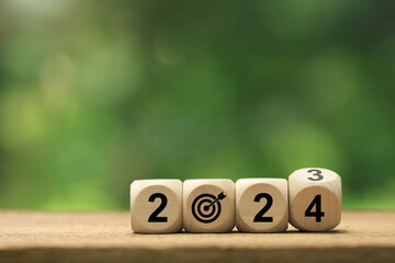 2024 New Year goal plan action. Wooden cubes with 2024 and target icon on a green background....