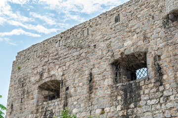 Ancient medieval stone wall with small lattice windows in the Old Town of Budva, Montenegro. Simple vintage architectural background with copy space