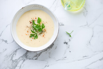 Bowl of cheese soup on a white marble background, horizontal shot with copy space, view from above