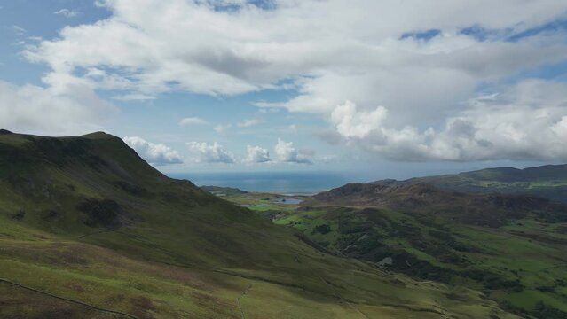 A drone footage of Cumbrian mountains with a lake seen in the distance.