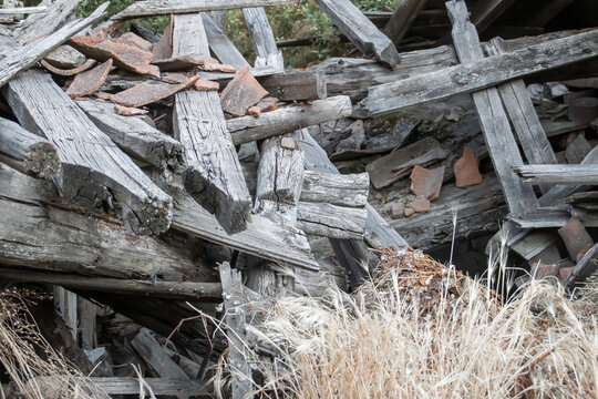 Tejado caído de una casa abandonada en un pequeño pueblo de Ávila, España. Detalle de las ruinas formadas por las vigas de madera y los restos de tejas de cerámica roja.