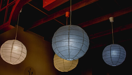 Lamps in the shape of balls are suspended from the ceiling in a group. Blue and beige lamps