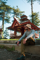 Young man sitting in  Shangchul mahadev temple in the meadow of Shahgarh, surrounded by Deodar Tree...