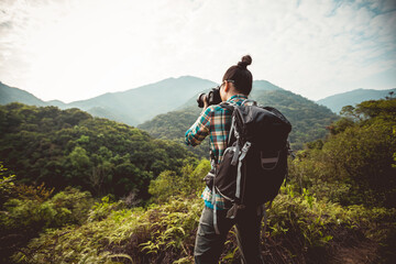 Woman photographer taking photo on morning mountain forest - obrazy, fototapety, plakaty