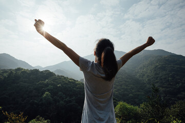 Cheering happy woman enjoying the view on morning mountain valley