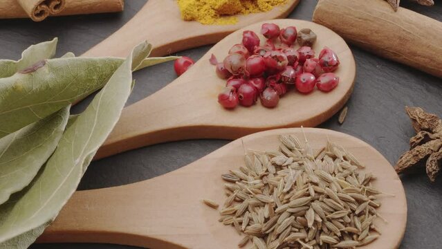 Various types of spices on wooden spoons slowly move along the frame, a great food background for your projects.