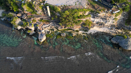 Aerial view of uluwatu cliff face, crystal clear water and blue sky