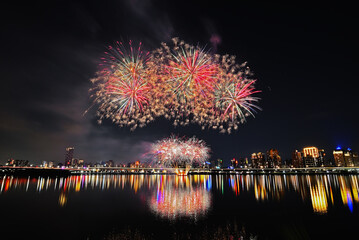 Naklejka premium Colorful fireworks of various colors over night sky with reflection in water