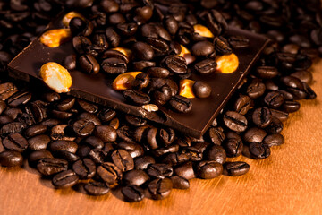 Coffee beans and dark chocolate with golden almonds on wooden background. - 648511409