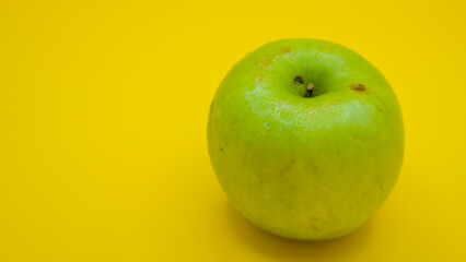 Close-up of fresh Granny Smith apple, green apple on yellow background with copy space