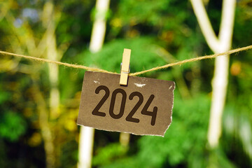 2024 on paper hanging on jute rope. Goodbye 2023 hello Happy New Year 2024 concept.