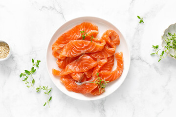 Salted salmon sliced on plate on a white background, top down view