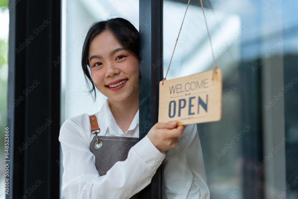 Wall mural young freelance businesswoman asian young female barista in apron holding sign preparing to open for