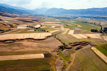 Aerial view of a rural landscape of grain fields and meadows in the mountains of Kyrgyzstan