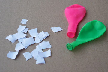 Green and pink balloon with no air and small pieces of paper. Concept, Science project work...