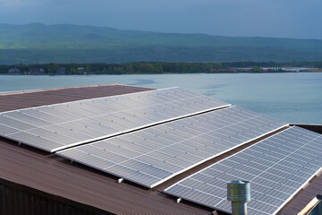 Close-up of solar panels on the roof of a house on the background of a lake, mountains