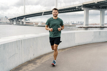 Male runner jogging in fitness clothes. Motivation and stimulation of fitness exercises. Athlete by...