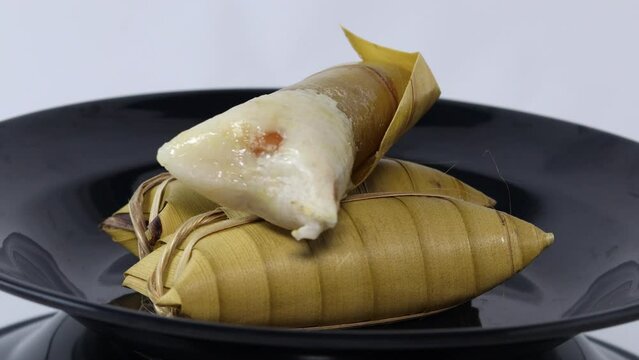 wrapped lepet is a kind of confectionery of glutinous rice mixed with peanuts, cooked in coconut milk, then wrapped in coconut leaves. serve on a black plate.
