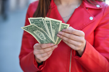 young woman hand counting one dollar bills on street