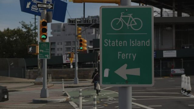 slow motion cyclist passes Staten Island Ferry bike lane sign