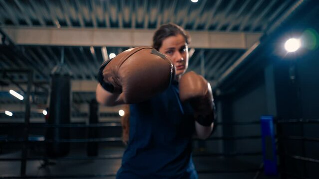 portrait of a woman in boxing gloves posing in a cheeky and competitive fight in a boxing ring before a fight with an opponent