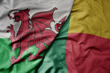 big waving national colorful flag of wales and national flag of benin .