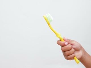 Child's hand holding a toothbrush, isolated on a white background with copy space