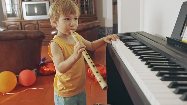 Little boy blowing the flute and playing the synthesizer