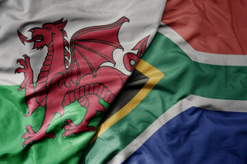 big waving national colorful flag of wales and national flag of south africa .